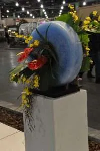 White acrylic display pedestal presenting a decorative sculpture at an exhibition stand.