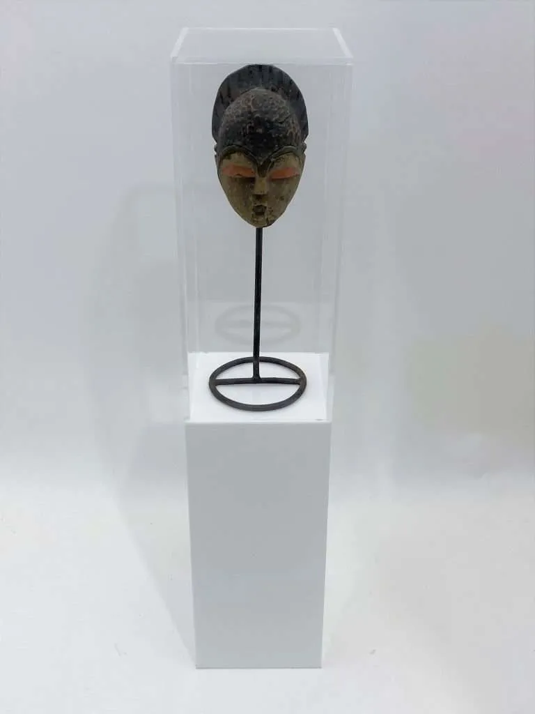 White acrylic pedestal with a clear display case housing a carved mask