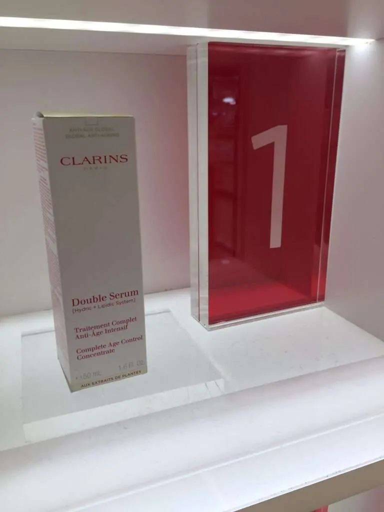 Clear acrylic riser beside a red acrylic block sign numbered one at a cosmetics display.