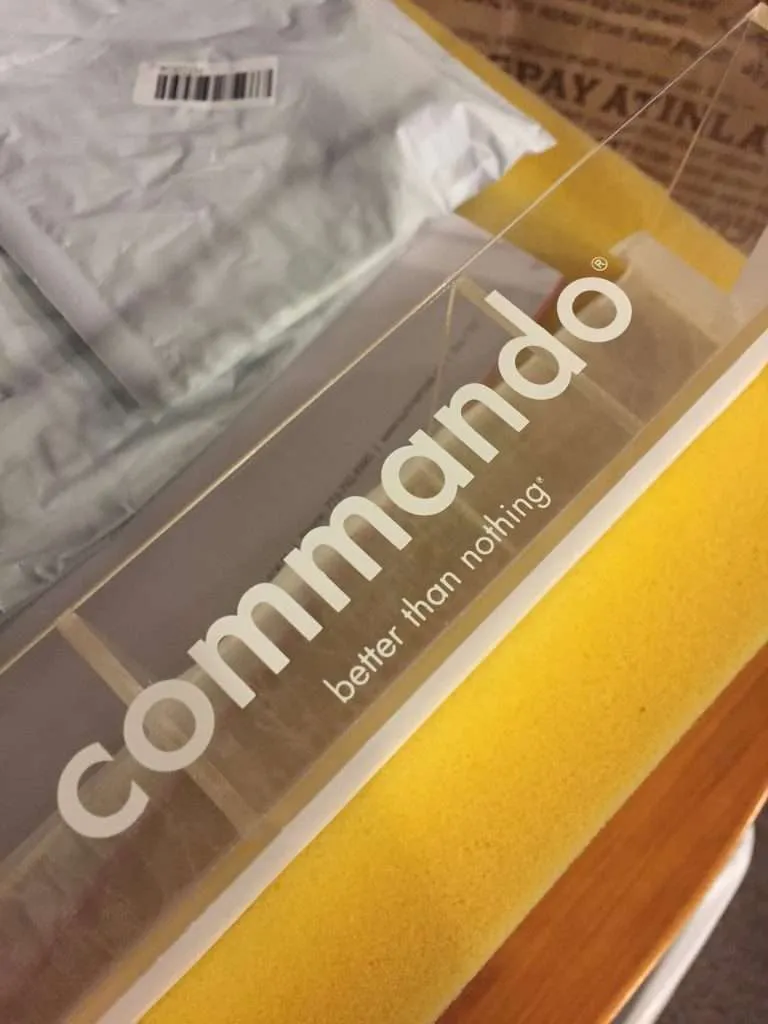 Clear acrylic display case with applied vinyl brand lettering, shown being packed for shipping.