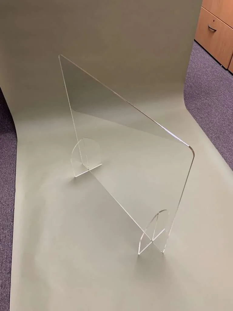 Clear acrylic countertop shield barrier with laser-cut circular feet on a floor