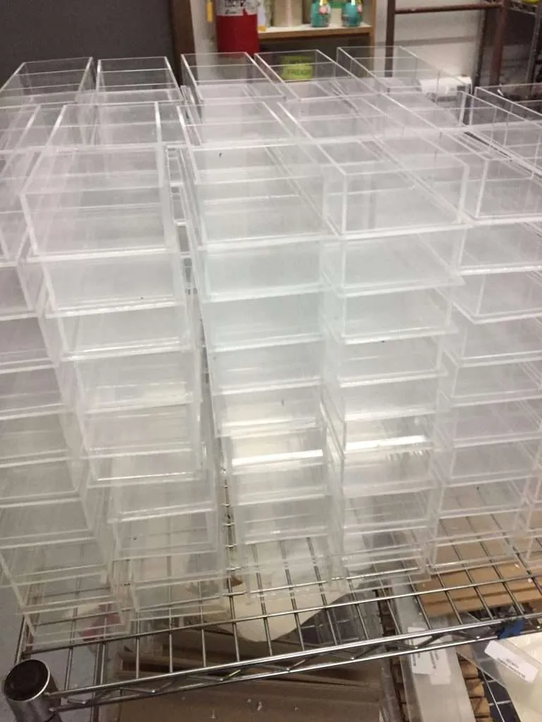 Stacks of fabricated clear acrylic display boxes on a shop rack.