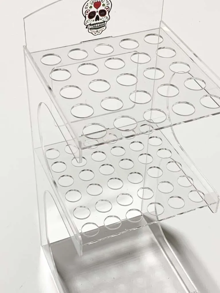 Clear acrylic tiered display with laser-cut round holes and a UV-printed skull graphic header.