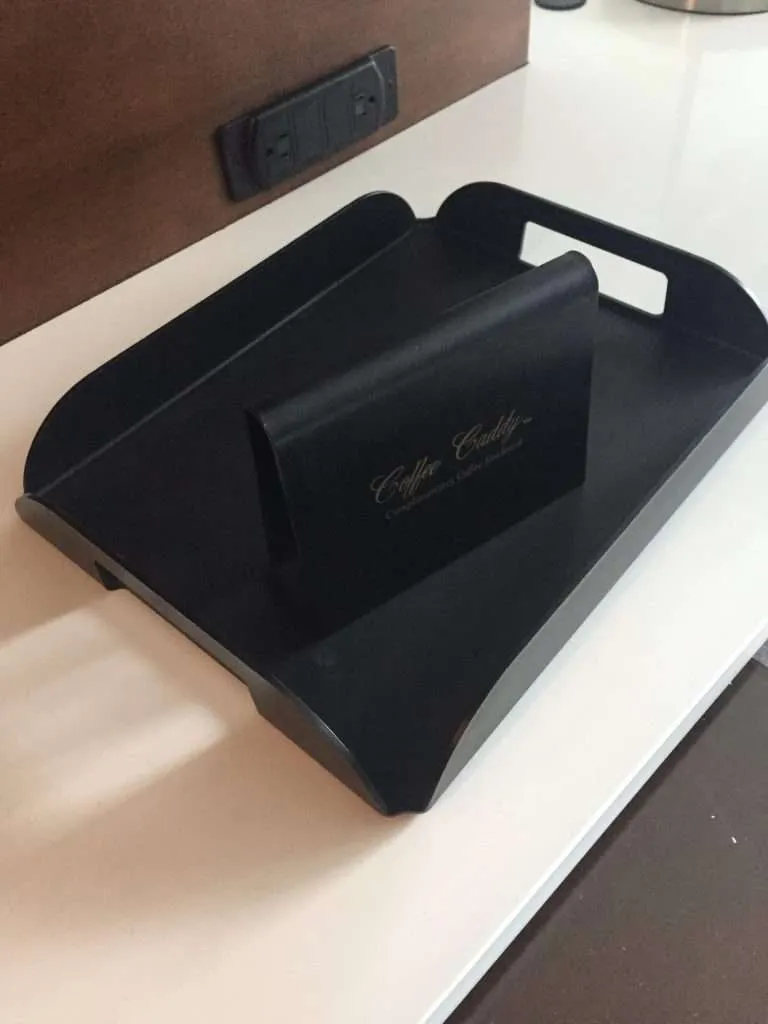 Matte black acrylic serving tray with cut handles and a printed tag.