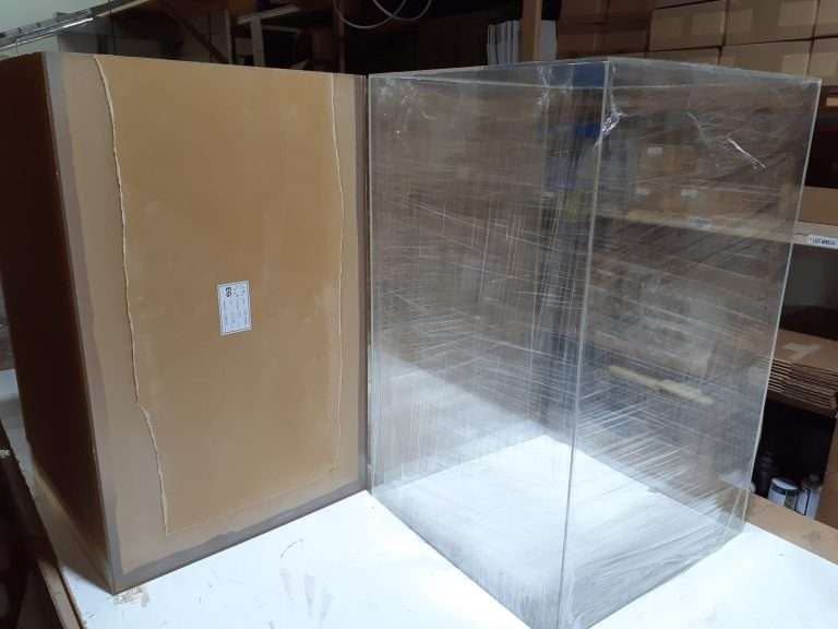Clear acrylic museum display case mounted atop a wooden flat-file drawer cabinet with an exhibit inside