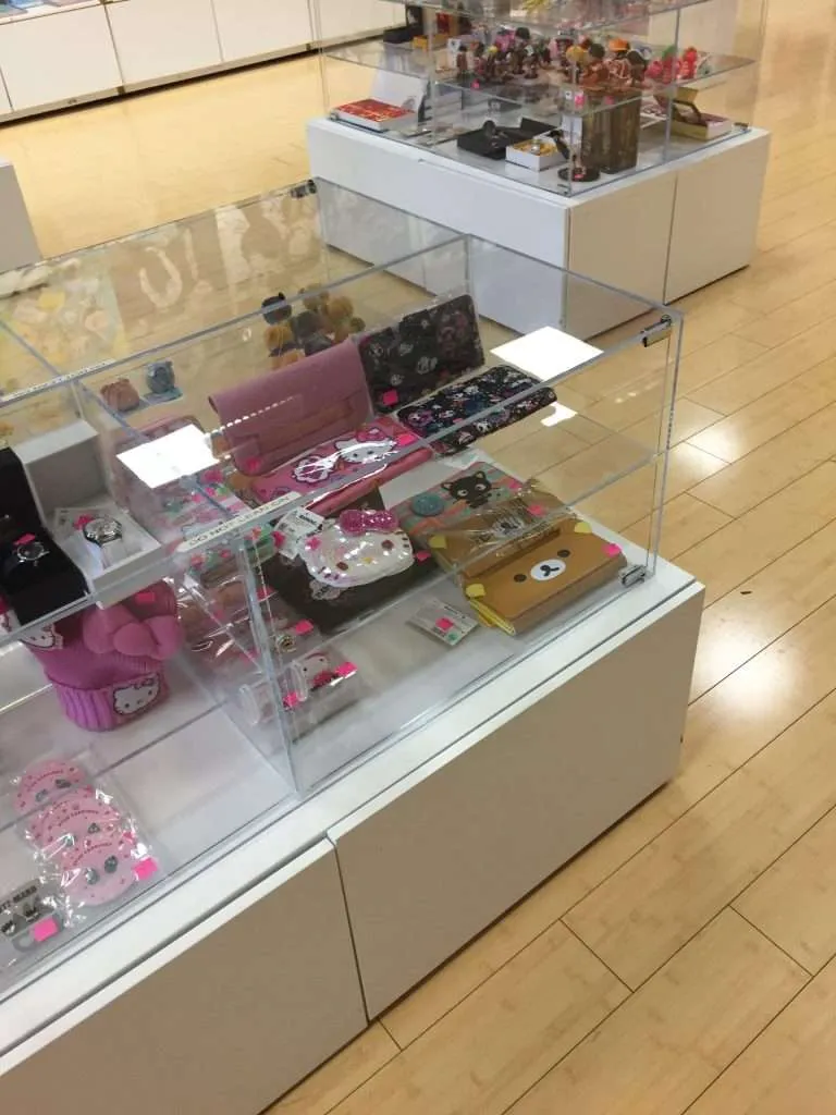 Clear acrylic countertop display case with a lockable hinged front, protecting small merchandise on a retail sales counter.