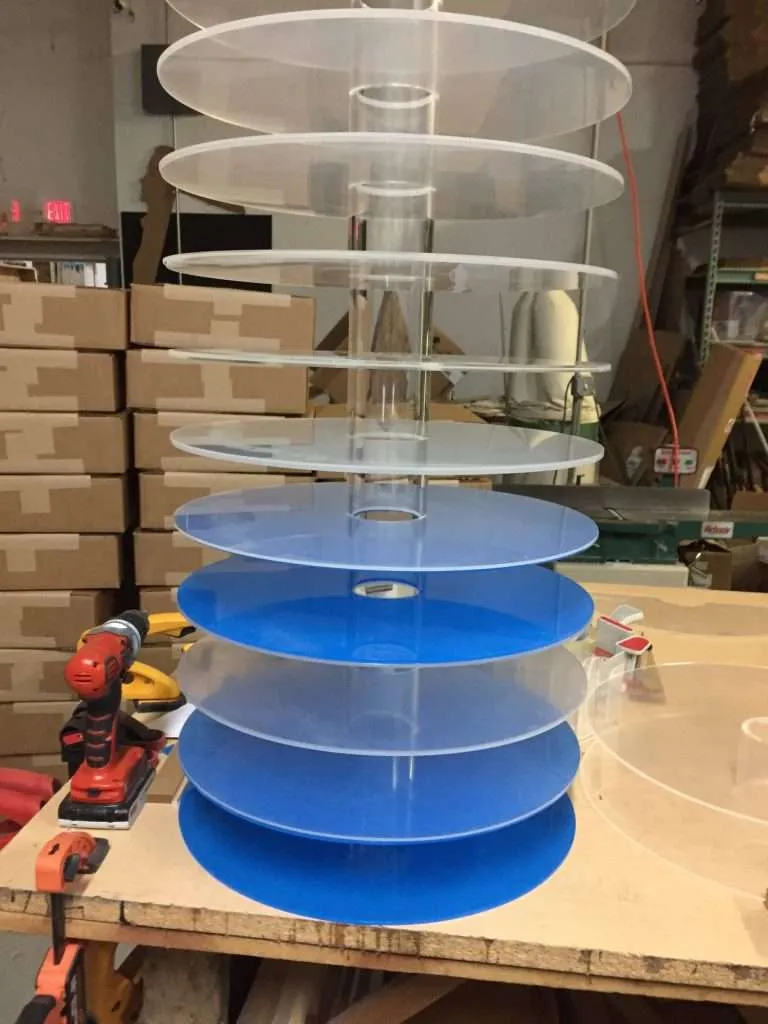 Stack of clear and blue circular acrylic display tiers in the fabrication shop.
